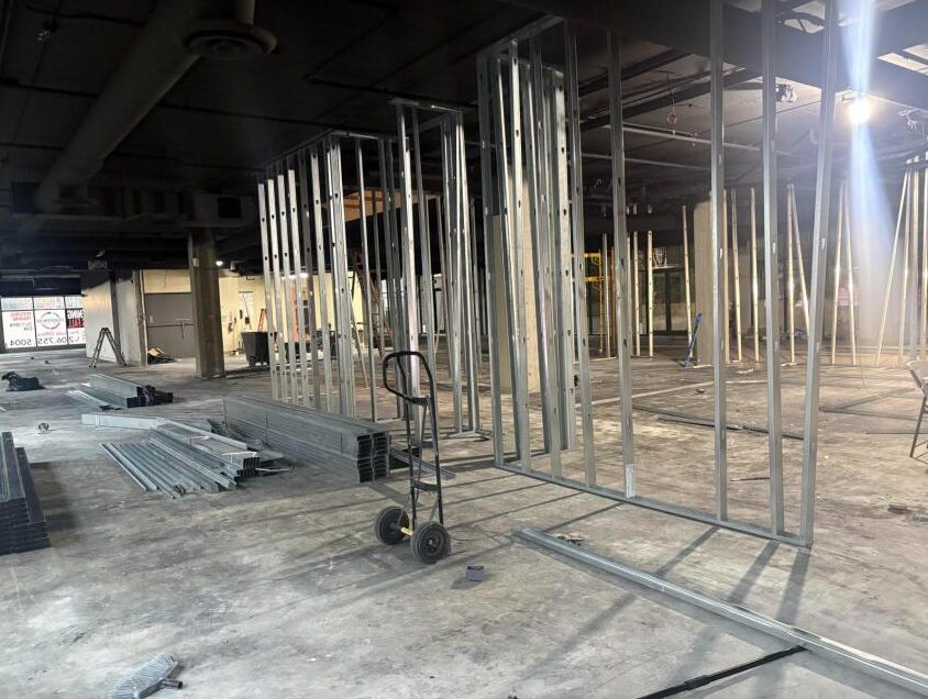 Metal stud framing going up across the Bellevue gym floor, October 2026